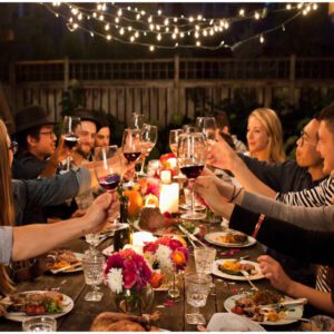 Friends enjoying dinner outside, raising their glass for a toast.